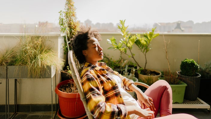 A woman enjoys the morning sun in her garden.