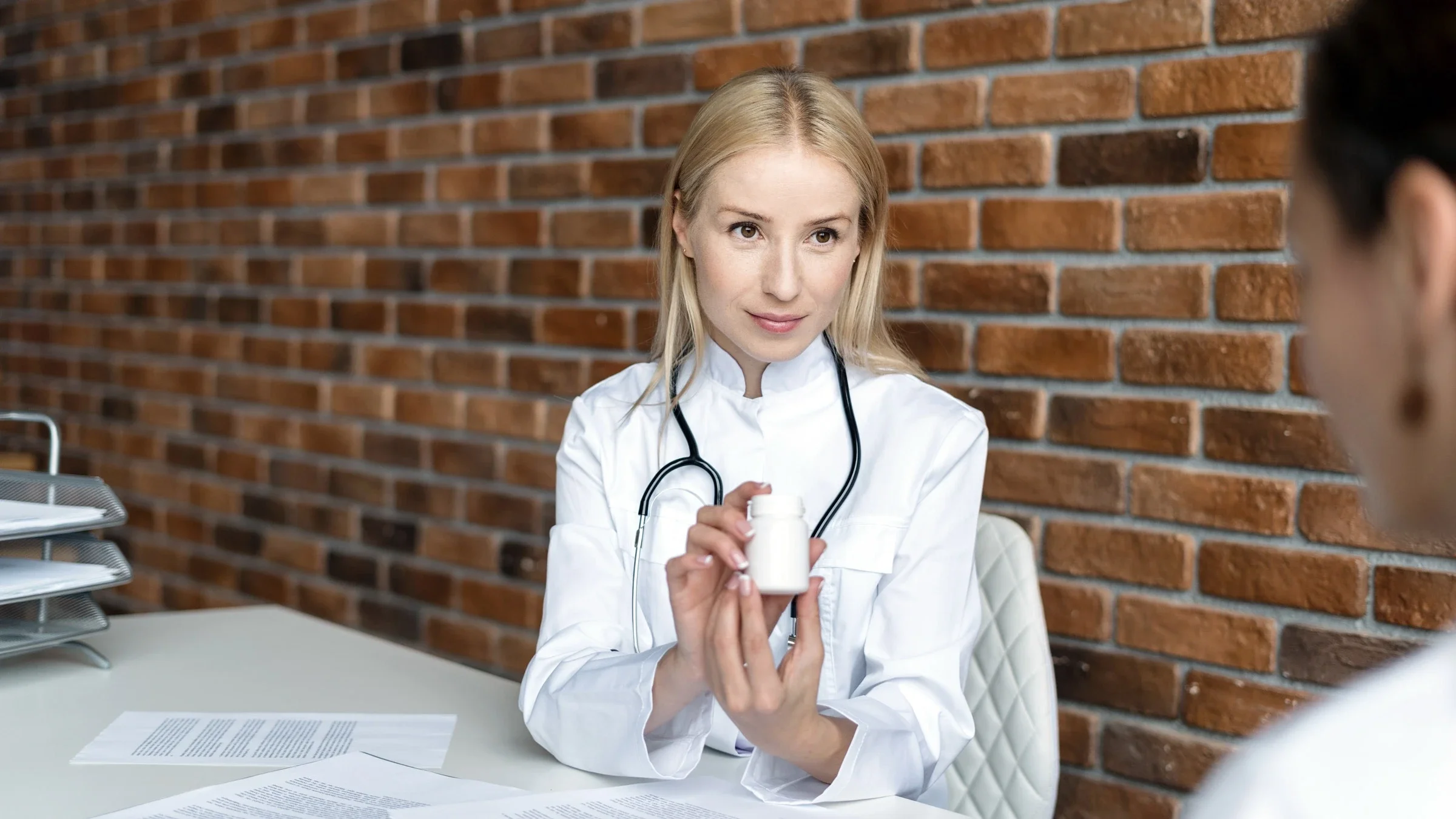 A HCP explaining a pill bottle to a patient.