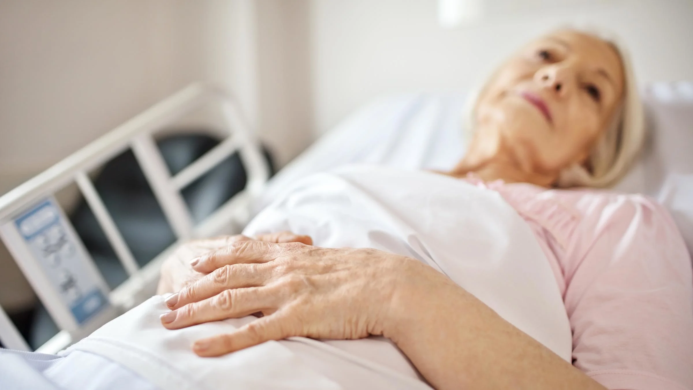 An older adult is lying on a hospital bed.