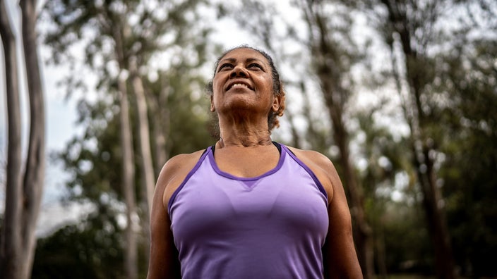 A woman smiles during an outing at a park. When a person reaches menopause, there are some self-care tips they can follow to relieve menopause symptoms.