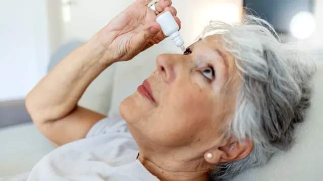 Eye: adult woman using eye drops 1987287145