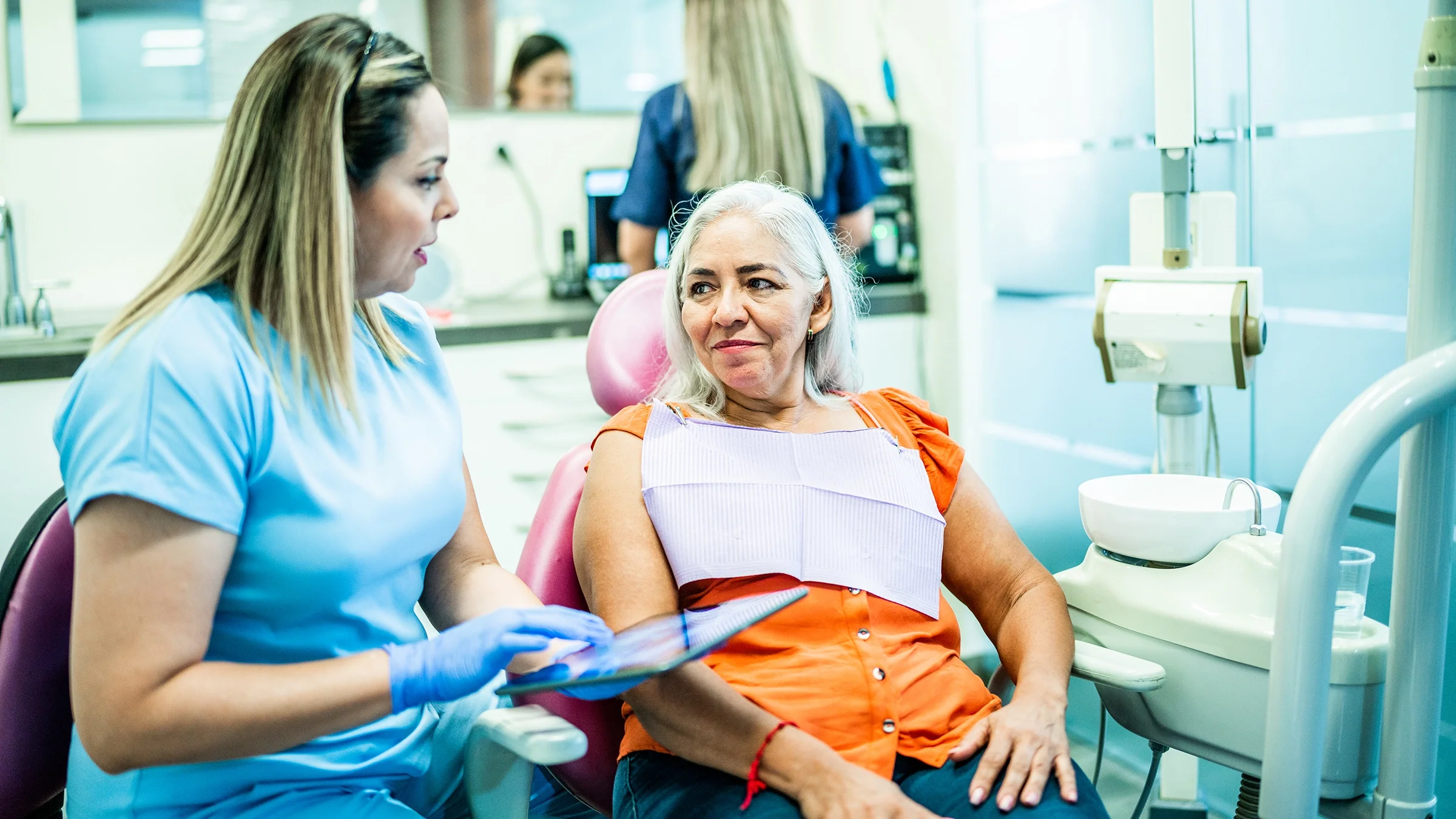 A dentist is discussing a woman’s X-rays with her.