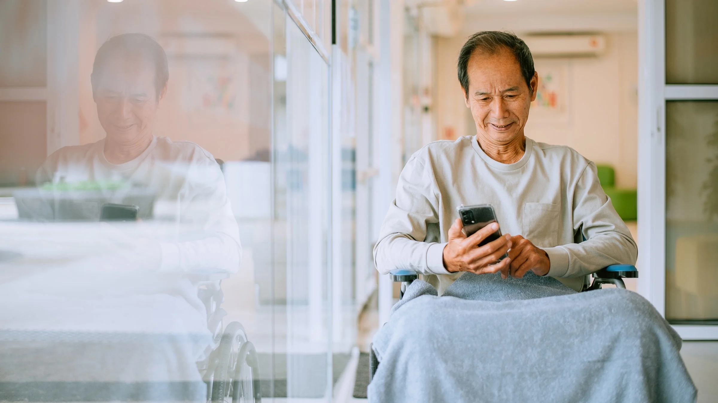 A cancer patient in a wheelchair using his phone.