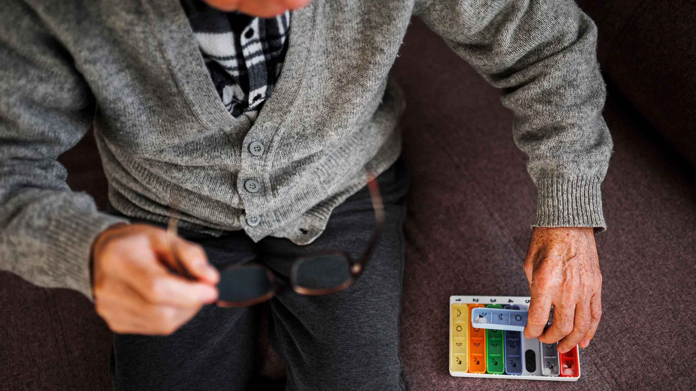 A man organizes medication into a weekly pill organizer.