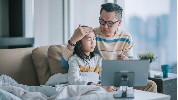 Father checking his child's temperature with his hand on their forehead.