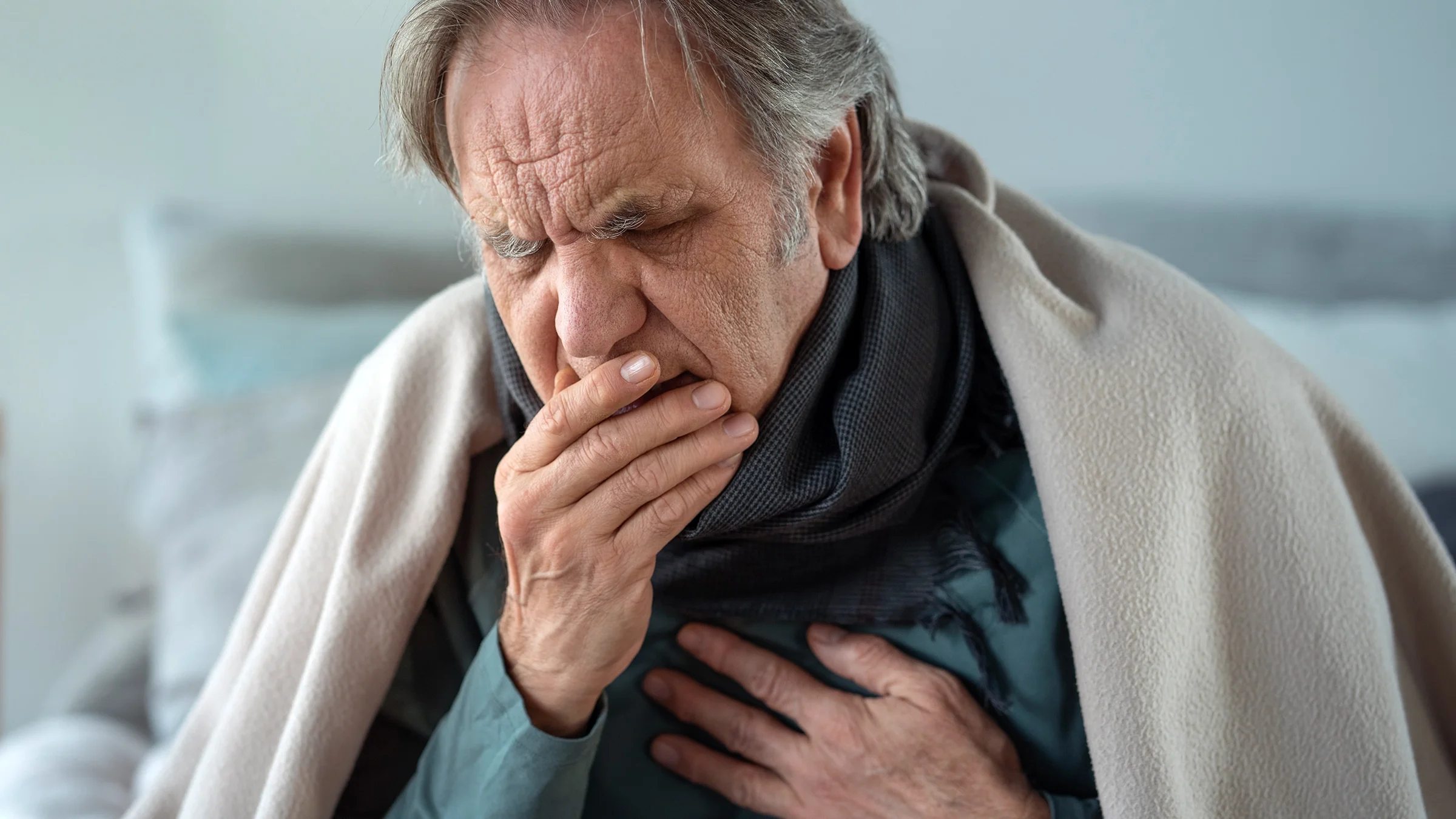 A man coughs while touching his chest. In some cases, the flu can develop into pneumonia.