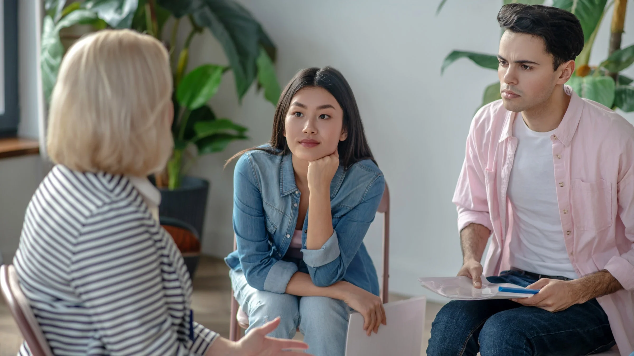A group therapy session. One person is speaking and the others are listening intently.