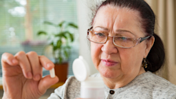 A person examining a pill and the bottle it came in. 
Suzi Media Production/iStock via Getty Images Plus 