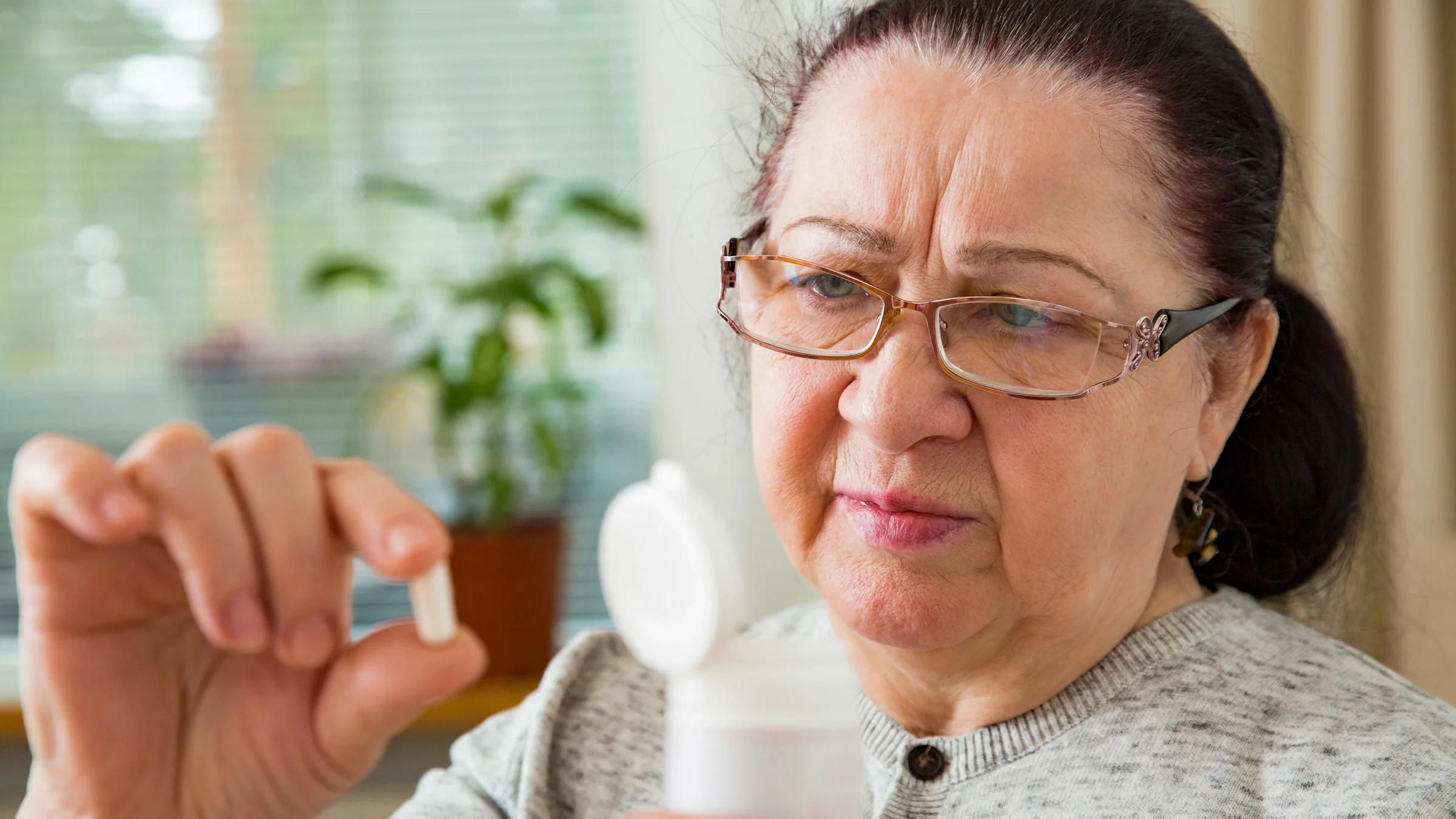 A person examining a pill and the bottle it came in.