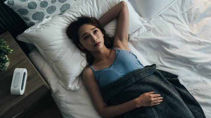 A person lying awake in bed, staring at their ceiling. 