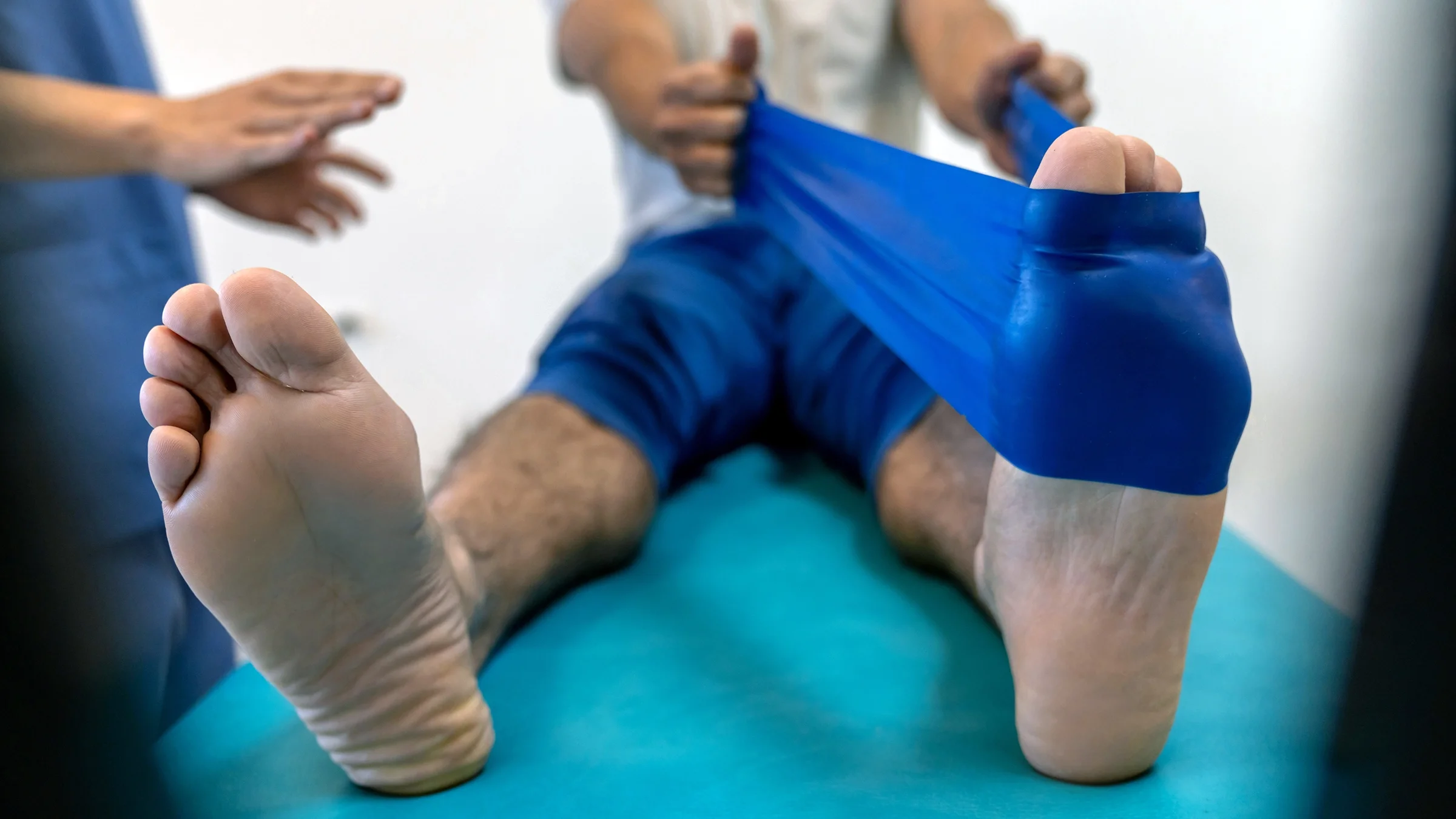 A man is stretching his calf with band around his foot in a close-up.