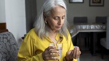 celecoxib: senior woman taking pill with water 1423526352