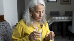 An older woman is taking a pill with water at home.
triloks/E+ via Getty Images 