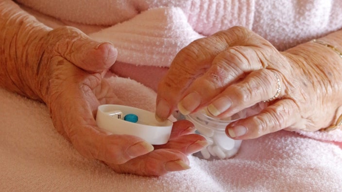Close-up of someone's hands taking pills out of a container.