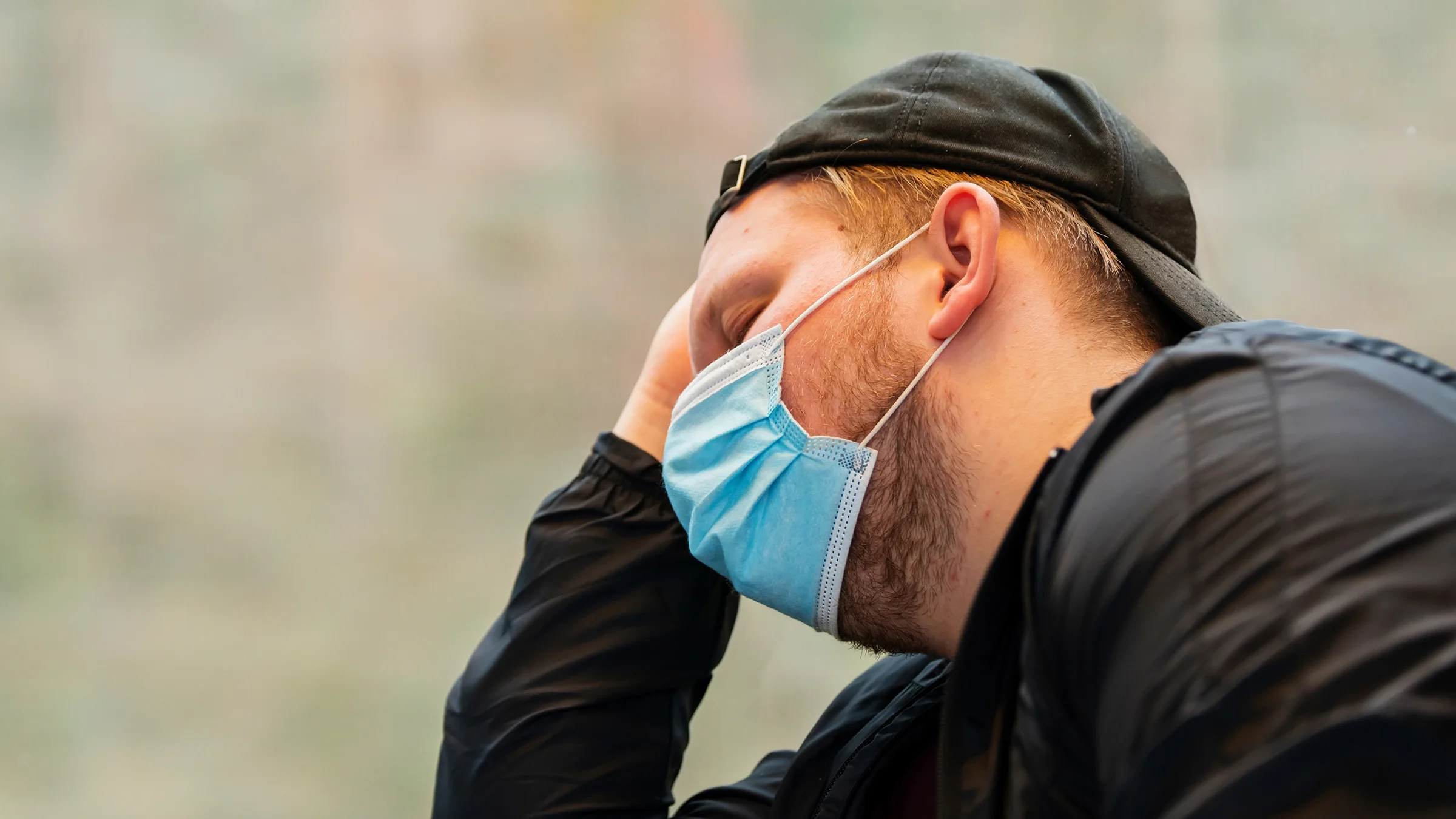 Larger man looking tired and overwhelmed while wearing a blue face mask.