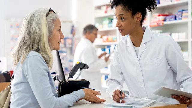 Medicare: woman speaking to pharmacist 1439988853