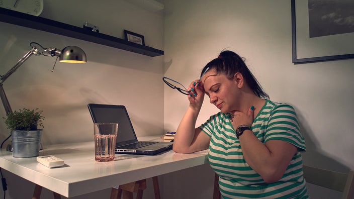 Woman with neck pain leaning on a desk.