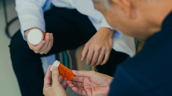 Cropped photo of a doctor and patient discussing two pill bottles.