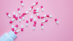 Pink and white capsules spill out from a plastic bottle onto a pink surface.
Fahroni/iStock via Getty Images Plus