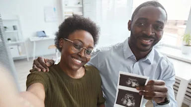 Future parents taking a selfie holding an ultrasound scan. 
SeventyFour/iStock via Getty Images