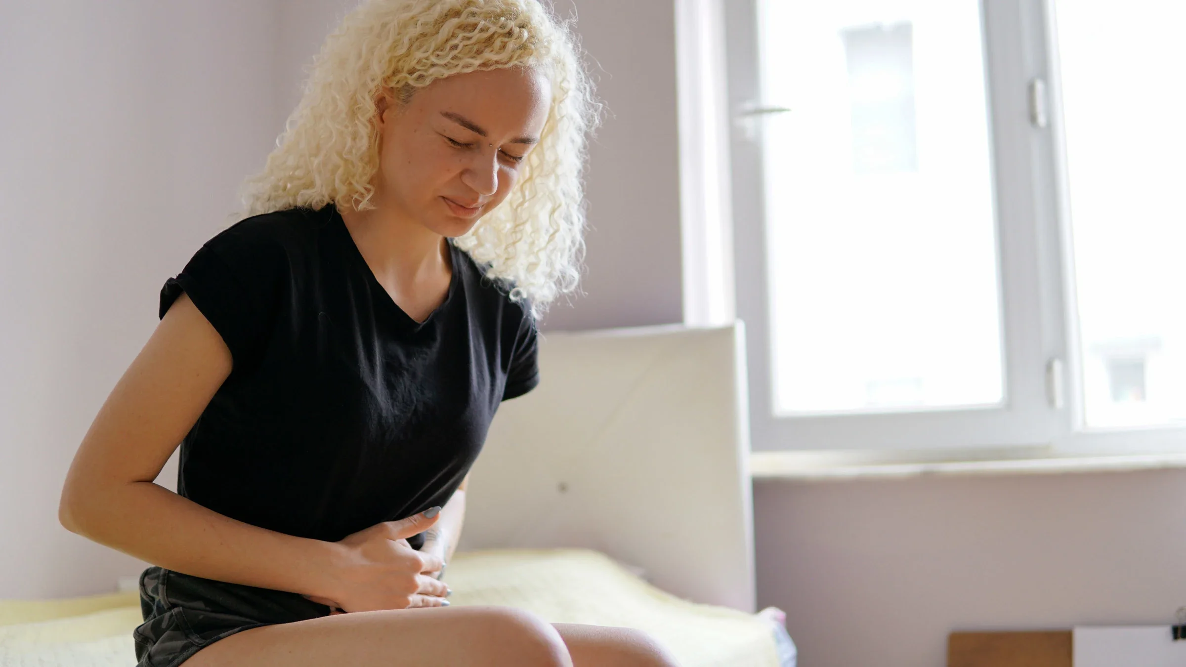 A person with abdominal pain sitting on their bed.
Alihan Usullu/iStock via Getty Images Plus 
