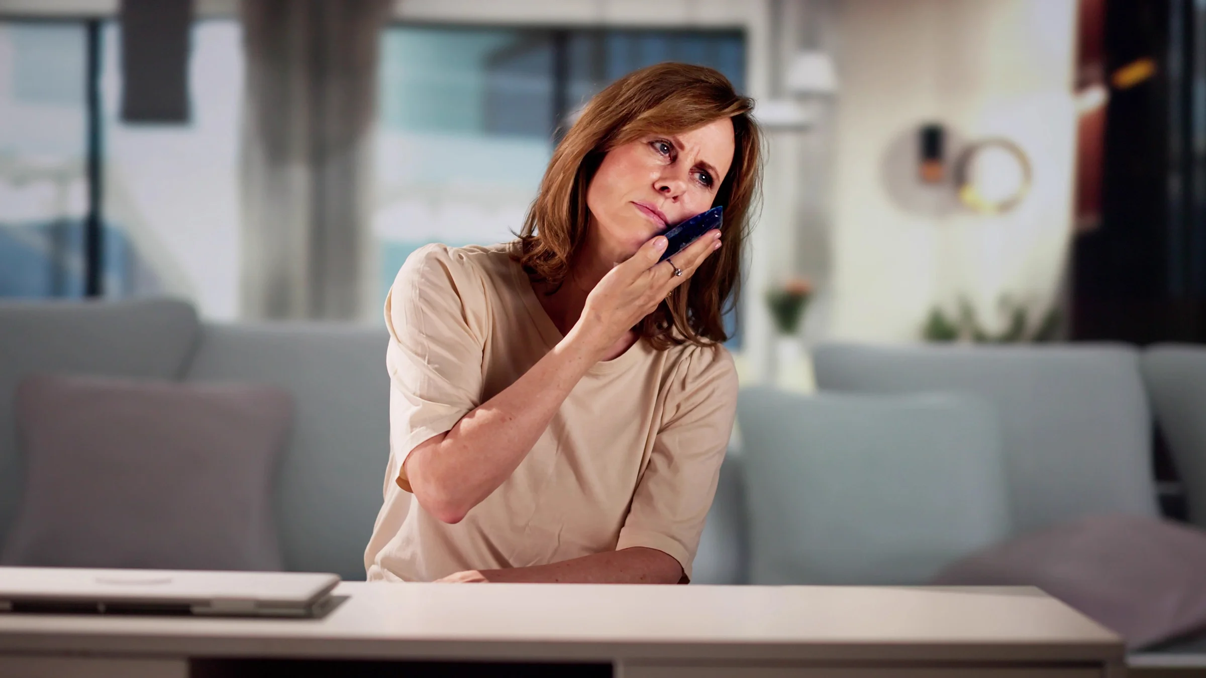 A woman holds a gel pack against her cheek to ease a toothache. 