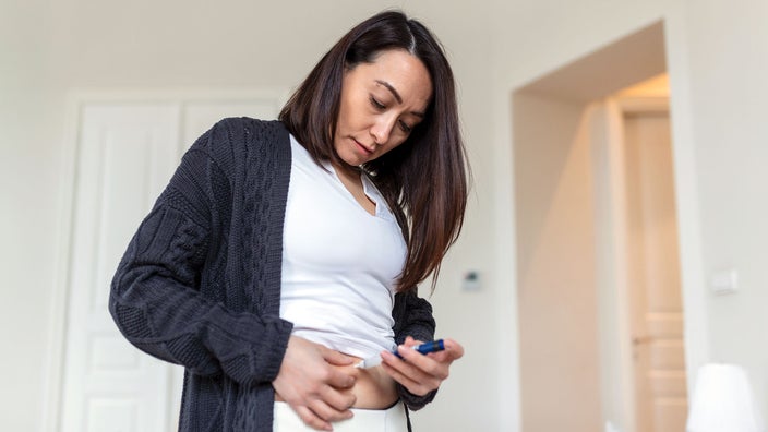 Woman Injecting herself in the stomach.