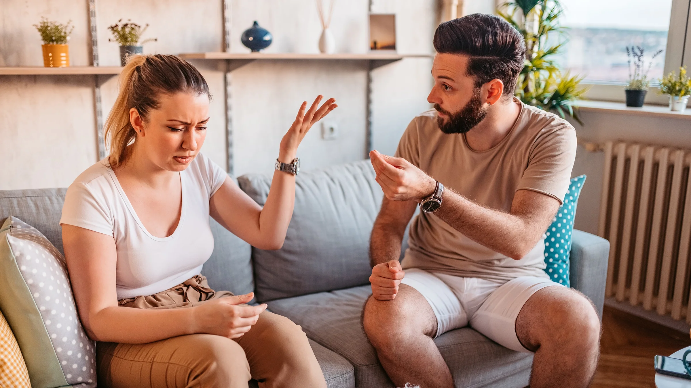 Couple arguing at home. Both are using their hands in expressive motions.