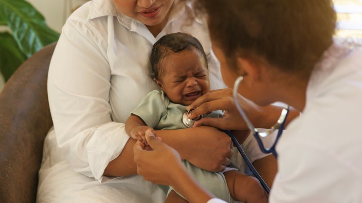 Baby crying sick at pediatrician checkup.