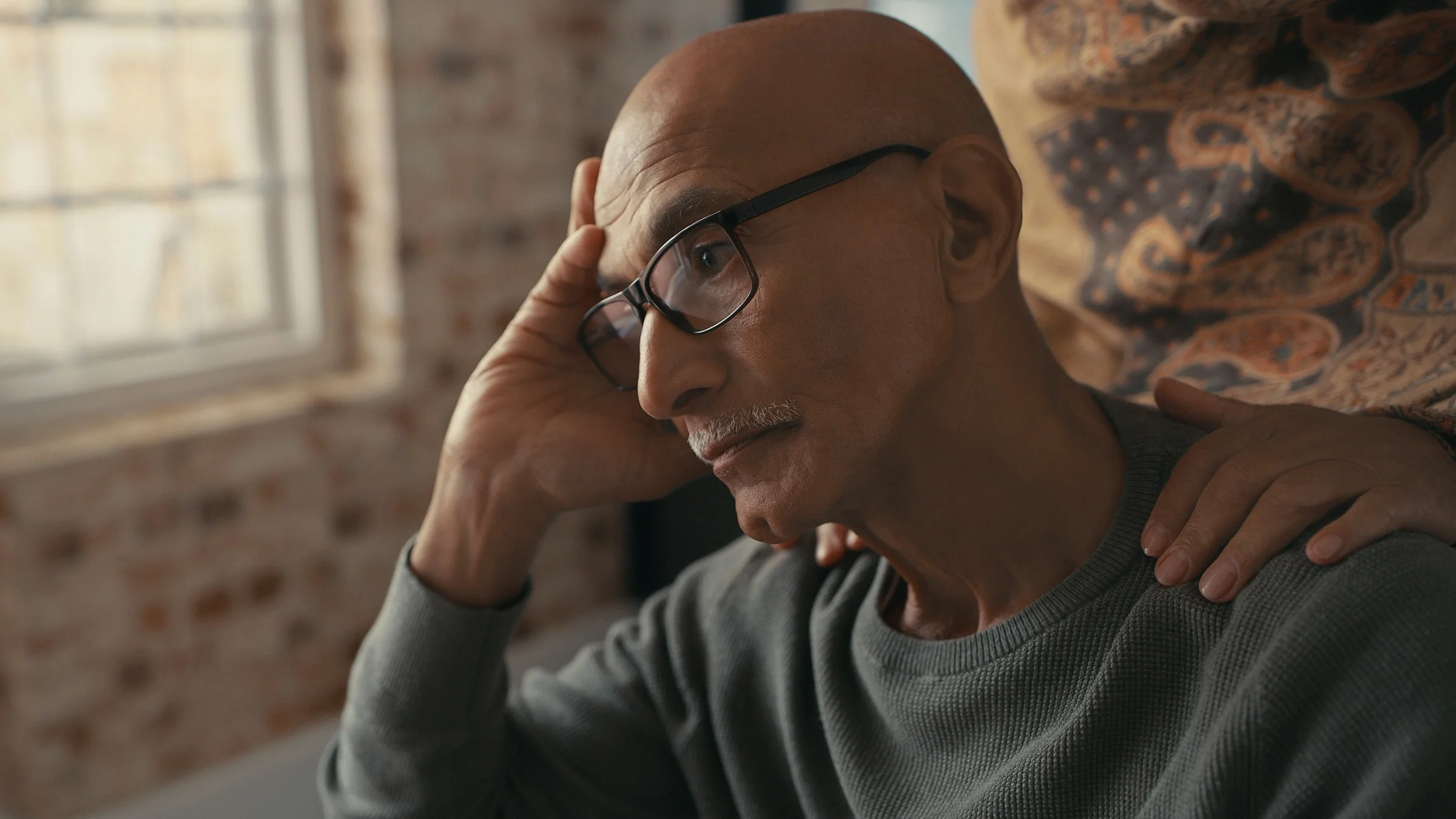 A depressed person with their spouse's hands on their shoulder.