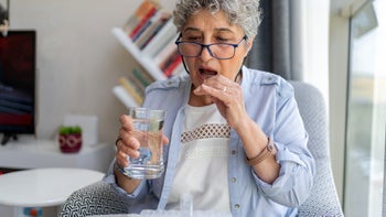 Nexletol: senior woman taking daily medication 1555550291