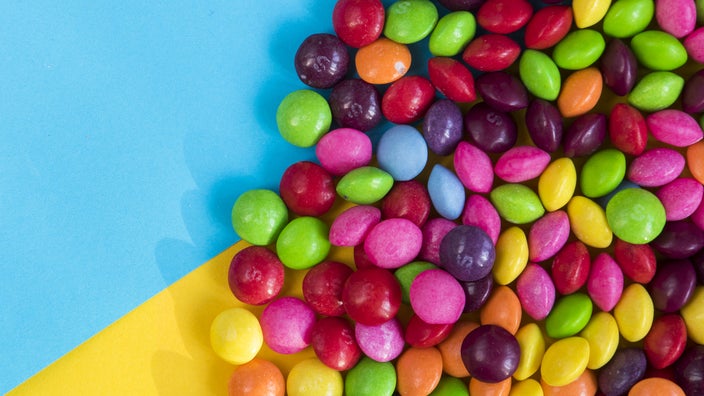 Skittles candies are shown on a colorful table.