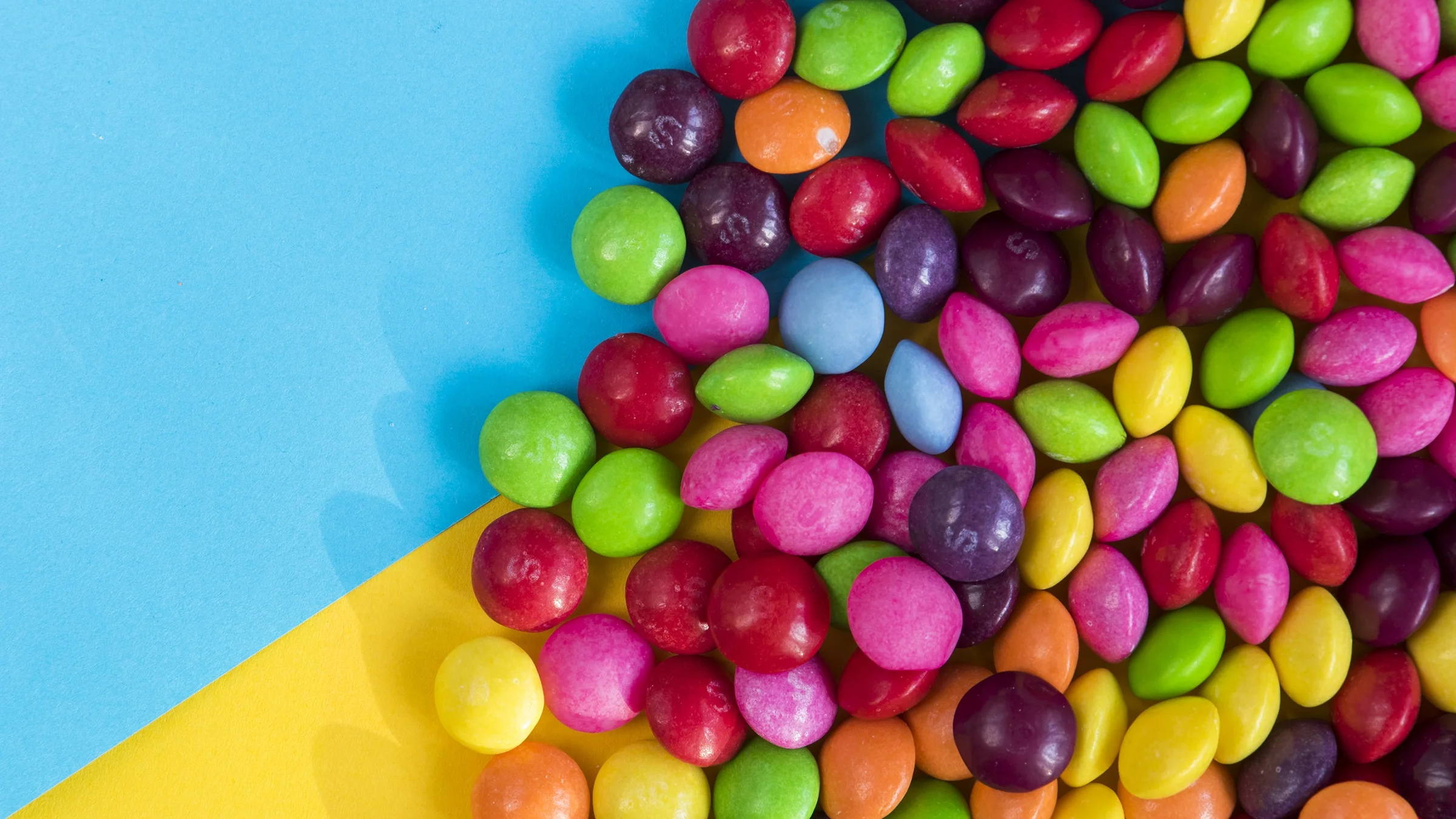 Skittles candies are shown on a colorful table.