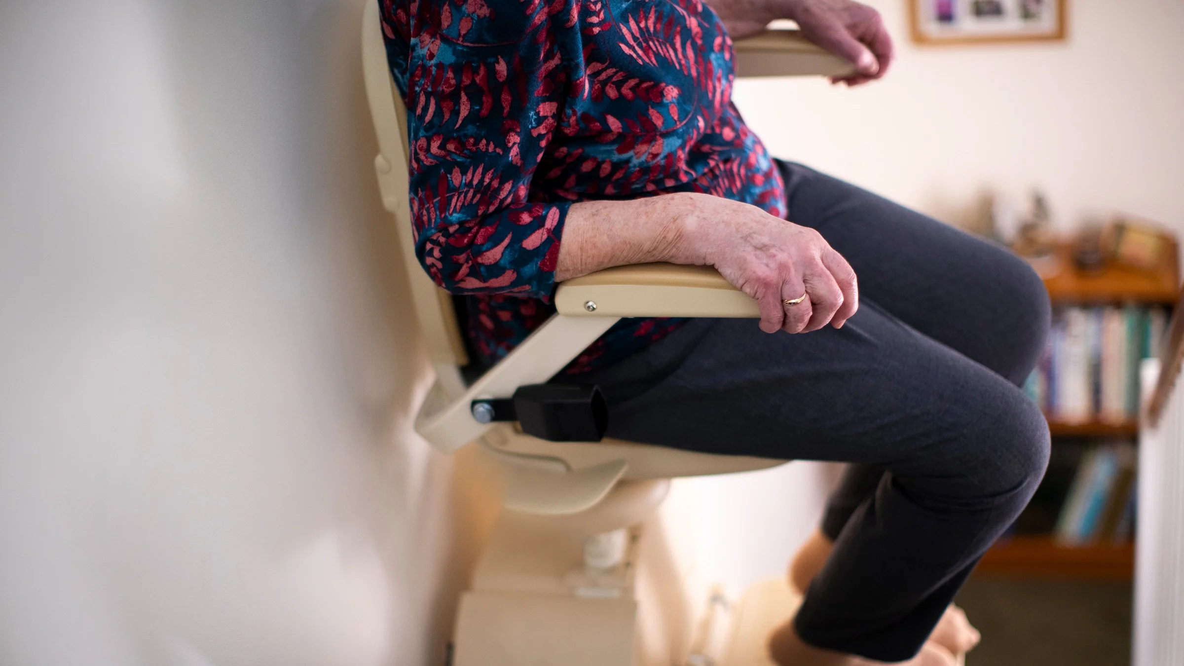 Close-up of an older woman on a stair lift in her home.