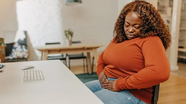 irritable-bowel-syndrome: stomach: pain: woman with abdominal pain at desk 1366957680