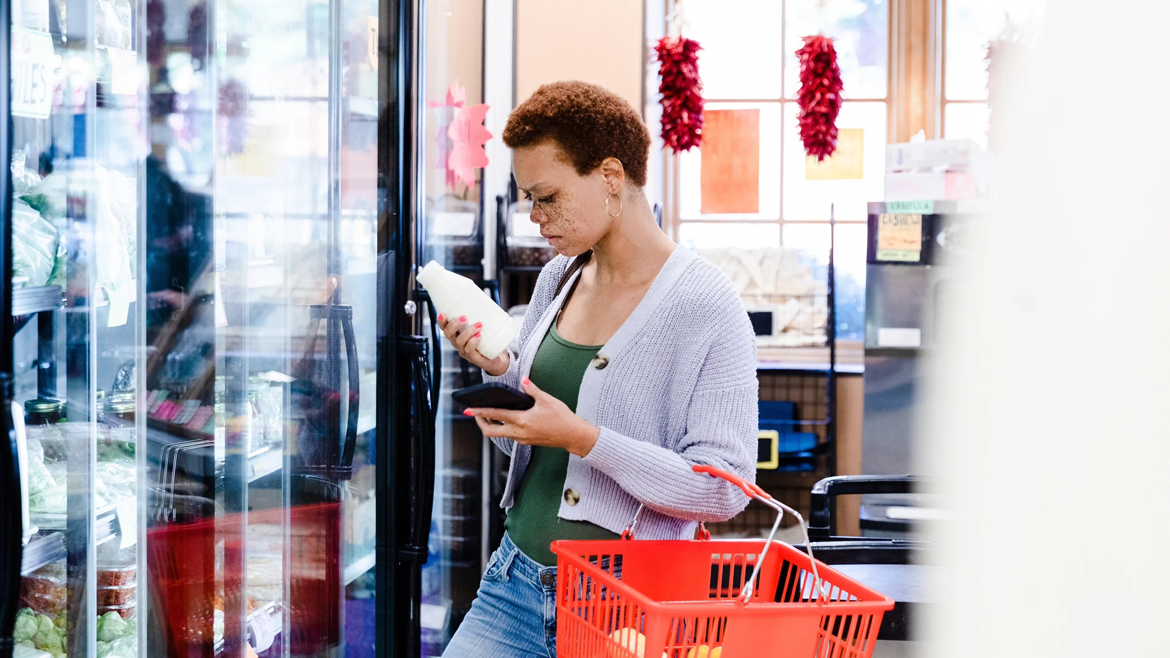 A woman reads the ingredients list on a milk bottle at a supermarket.