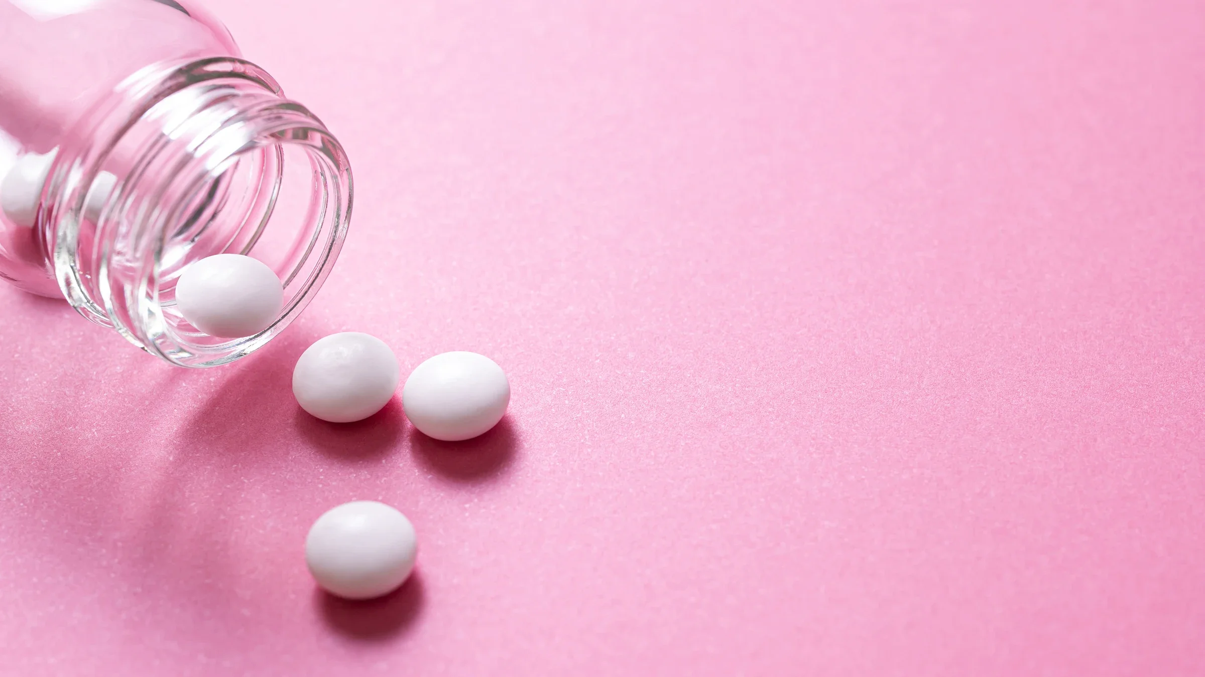 Health: emergency contraceptive: white pills pink background glass bottle-1339372592