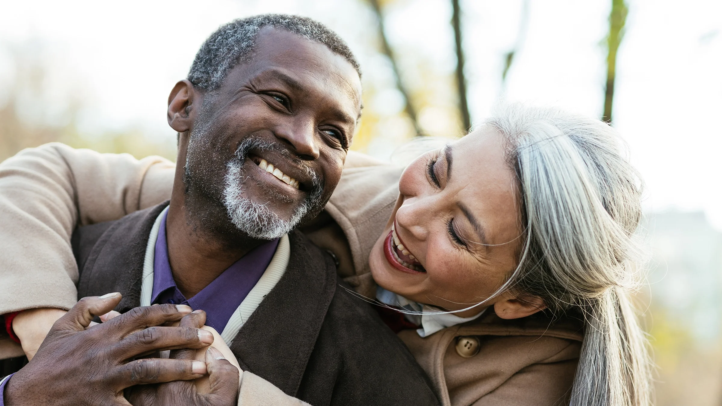 Couple embracing and smiling outside on a cold day.