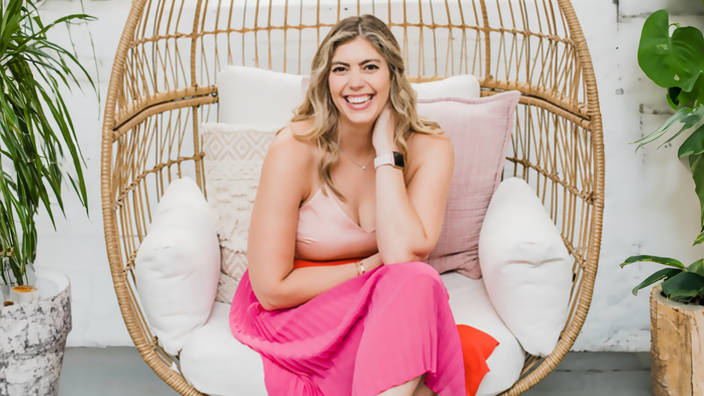 Courtney DuBois Shihabuddin is pictured sitting on a wicker swing, indoors.