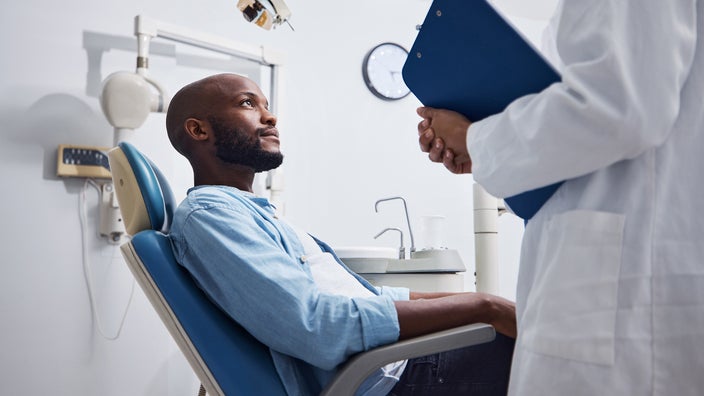A person is speaking to their dentist at an appointment.