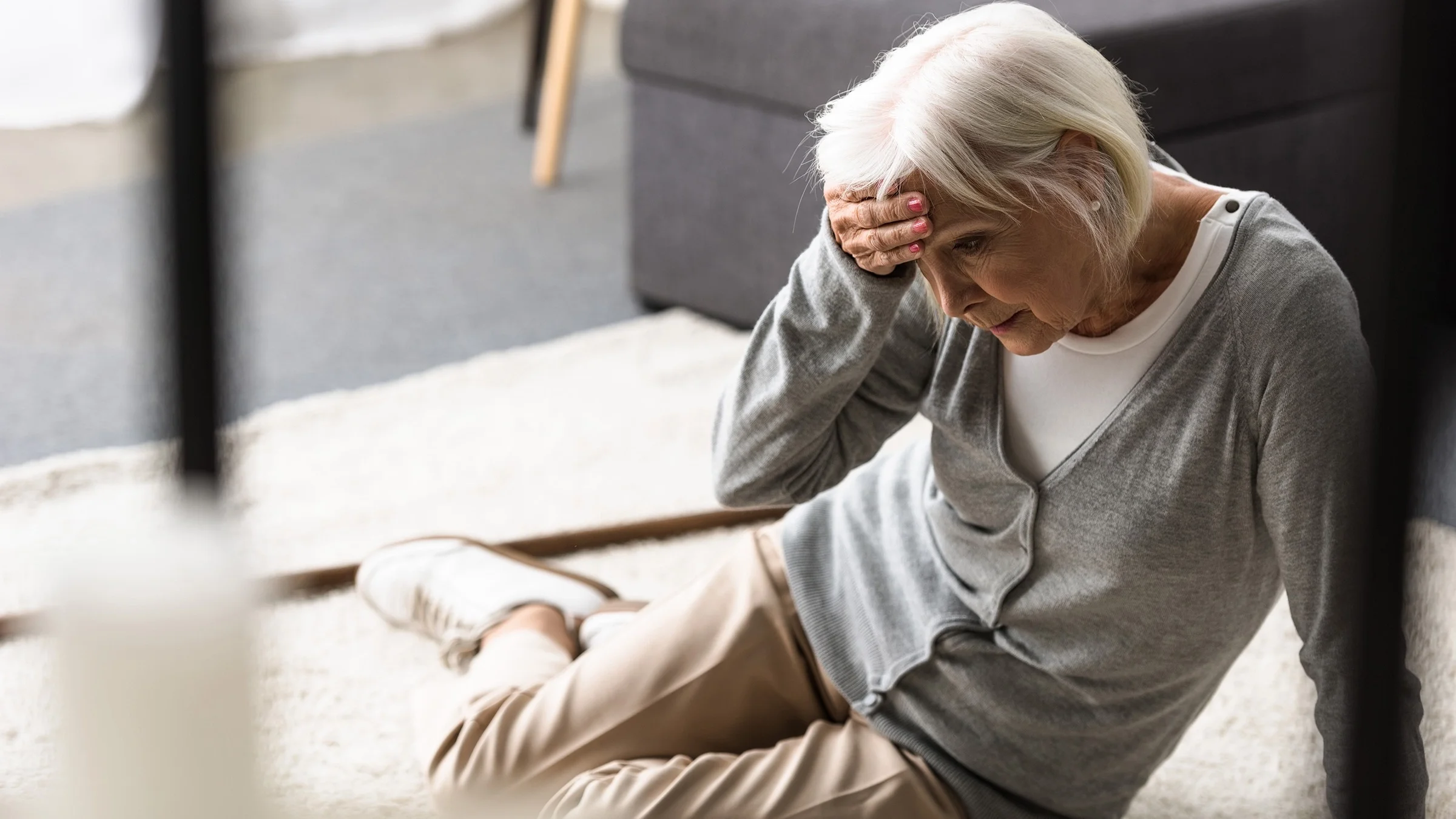 Senior woman fallen on the ground with her hand on her forehead.