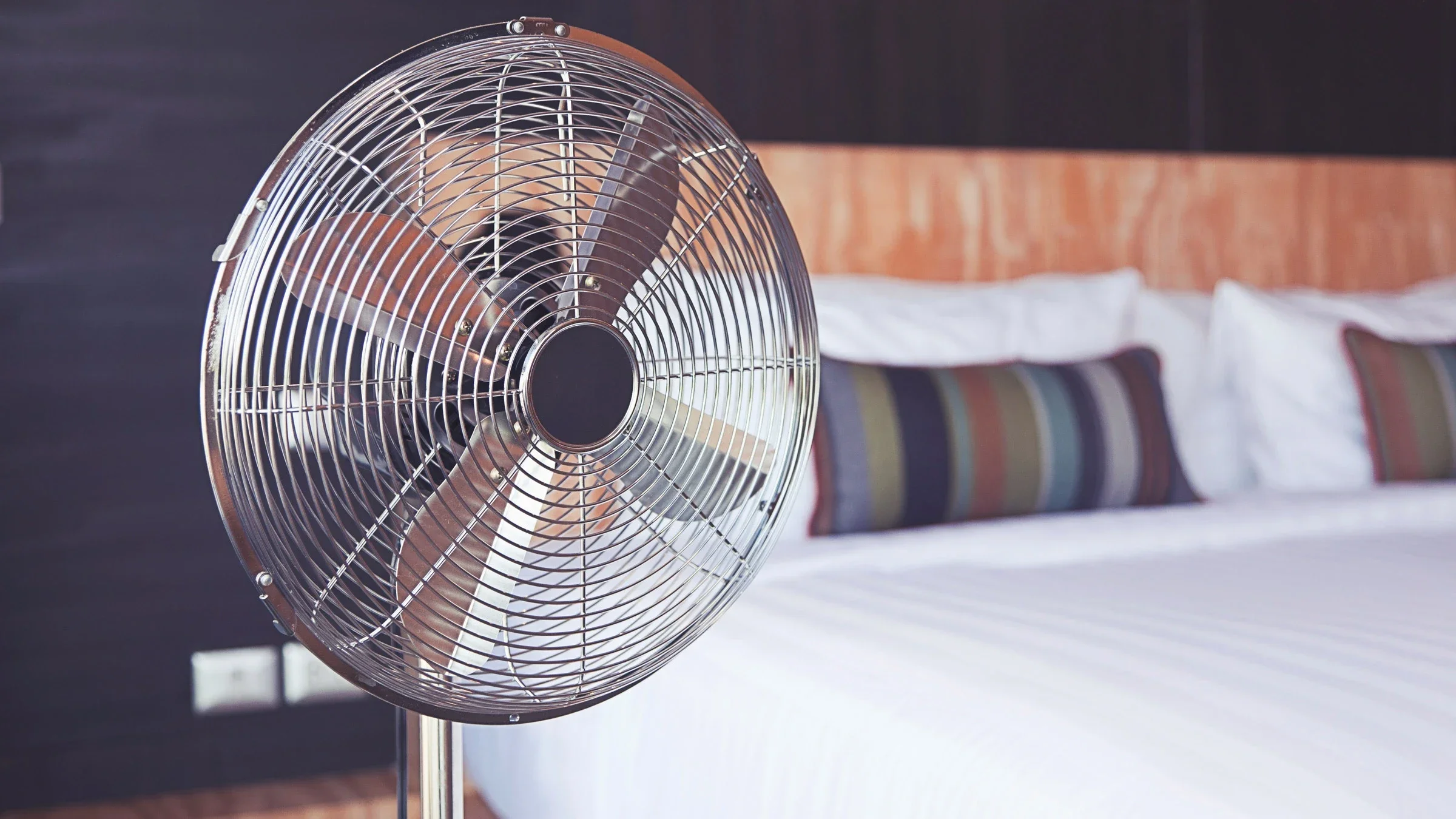 An electric fan placed next to a bed.
ben-bryant/iStock via Getty Images