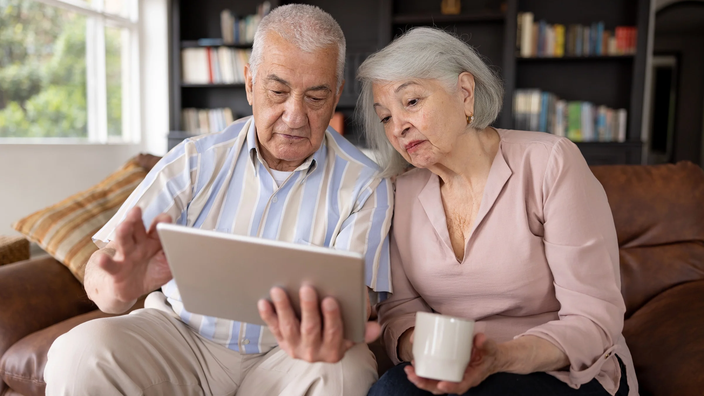 An older adult couple is reading on a tablet.