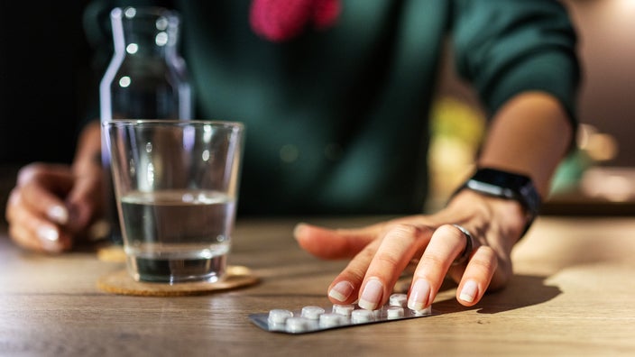 A woman pictured with a blister pill pack and glass of water.
