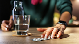 A woman pictured with a blister pill pack and glass of water.
simonkr/E+ via Getty Images