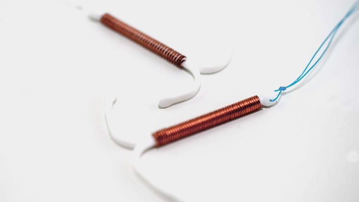 Close-up of two copper IUDs on a white background.