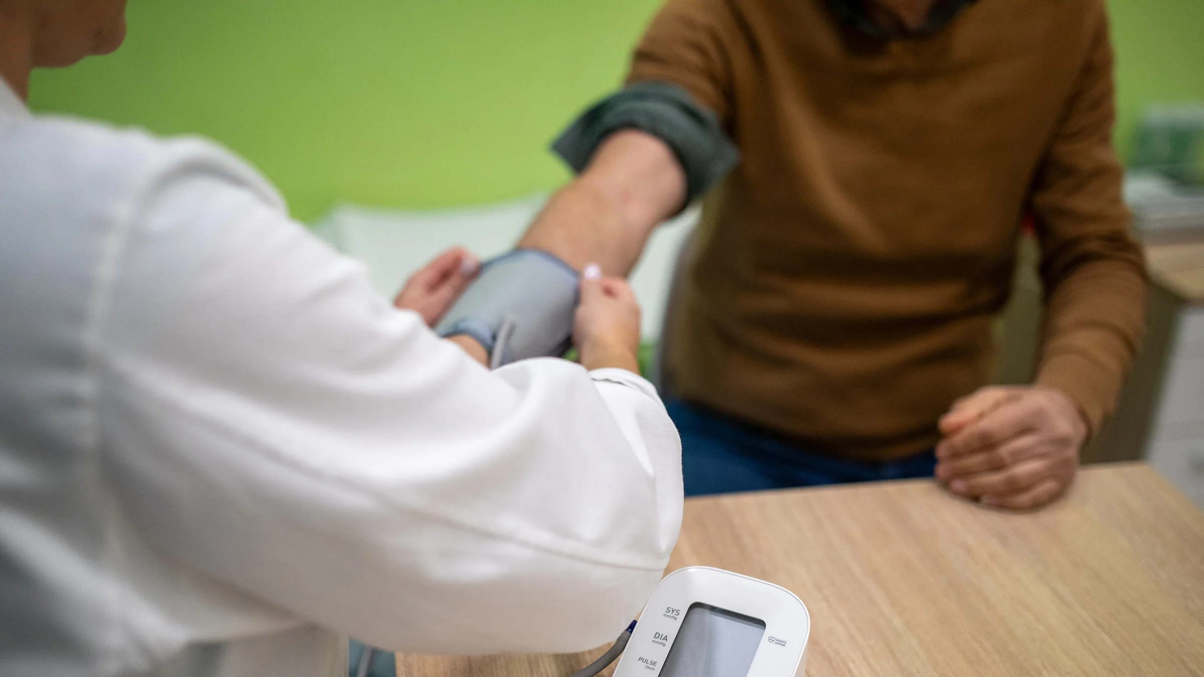 A healthcare professional measures a man’s blood pressure in a medical clinic.