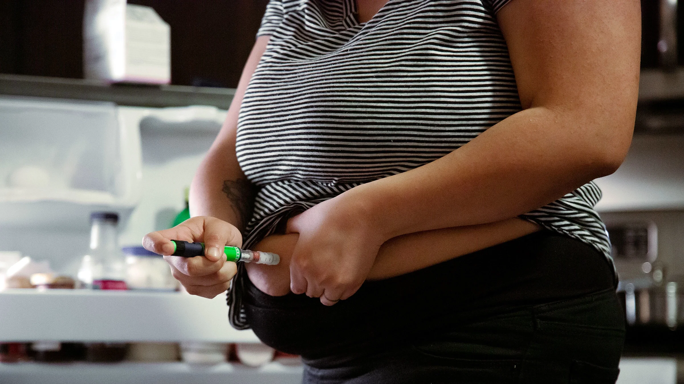 A woman injects a weight loss medication into her stomach.