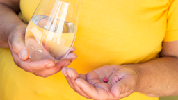 Close-up shot of a hand holding a pill and a glass of water.
sanjagrujic/iStock via Getty Images Plus