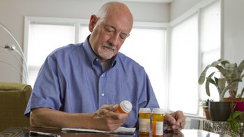 Medication Education: Dosage: senior man reading Rx label 179812576